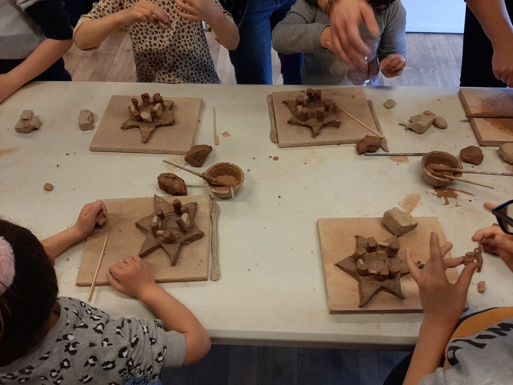 Quatre enfants participant à un atelier de poterie.