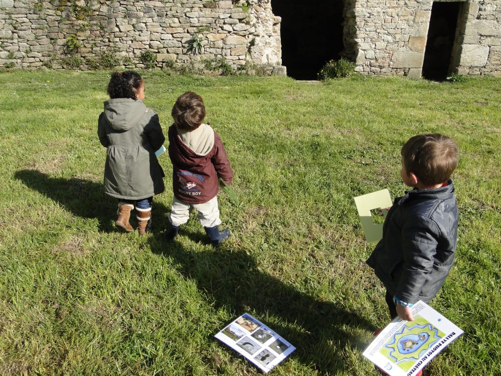 Trois enfants dans la cour du château avec les supports de médiation du rallye photo.