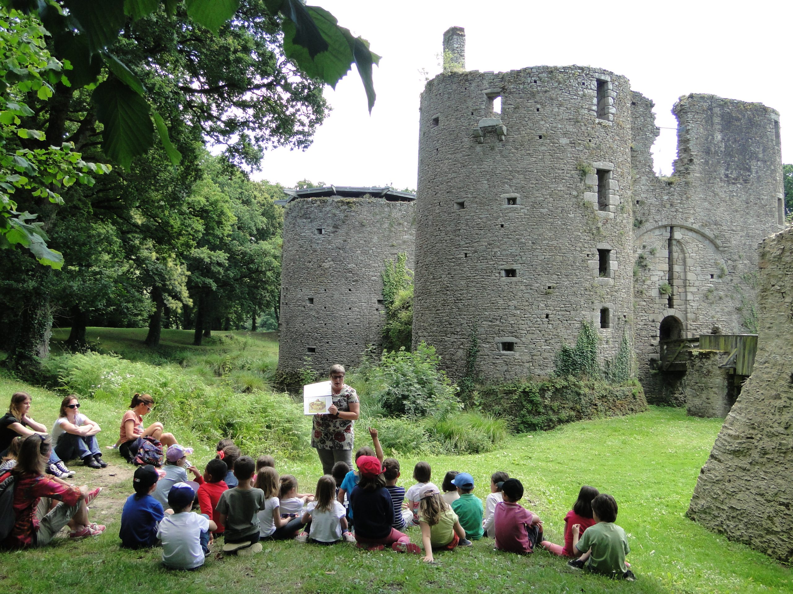 Un groupe d’enfants près des douves du château, écoutant la médiatrice.