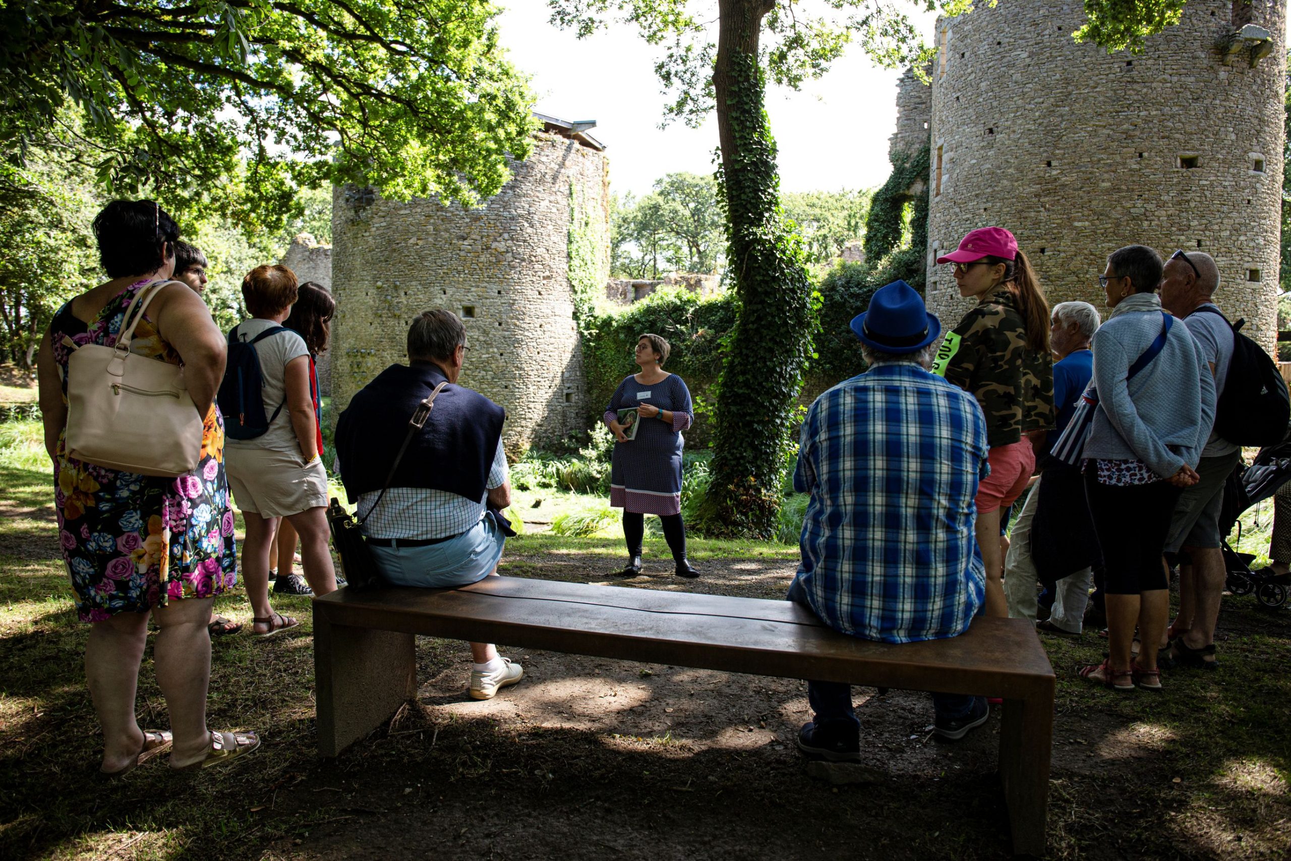 Un groupe de visiteurs rassemblés autour d’une médiatrice qui explique l’histoire du château autour des douves.