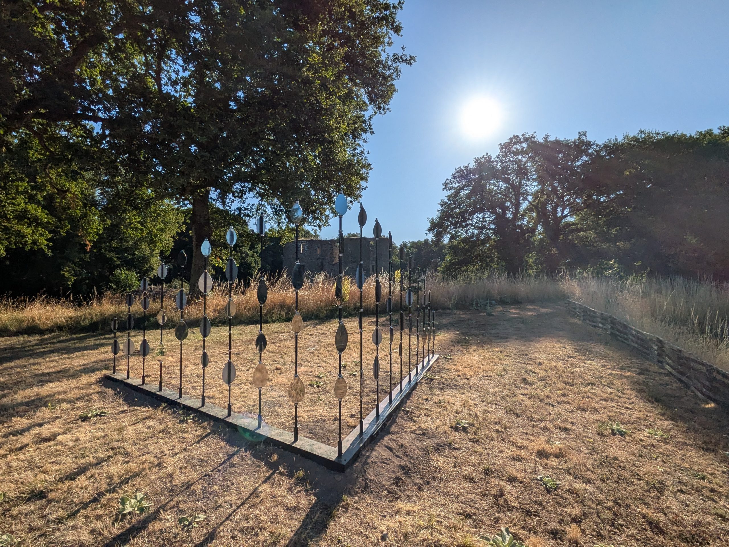 Œuvre du duo Scenocosme : sculpture en fer avec des miroirs en forme de gouttes disposés en pyramide, reflétant la lumière du soleil.